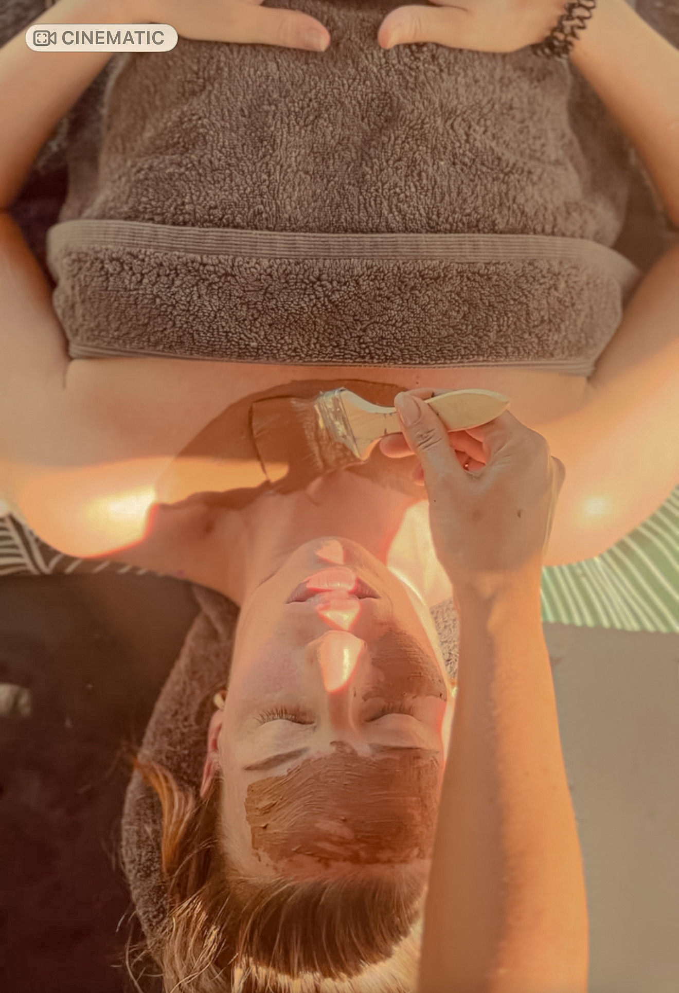 A natural clay mud mask being applied with a brush during the head massage and mud mask treatment